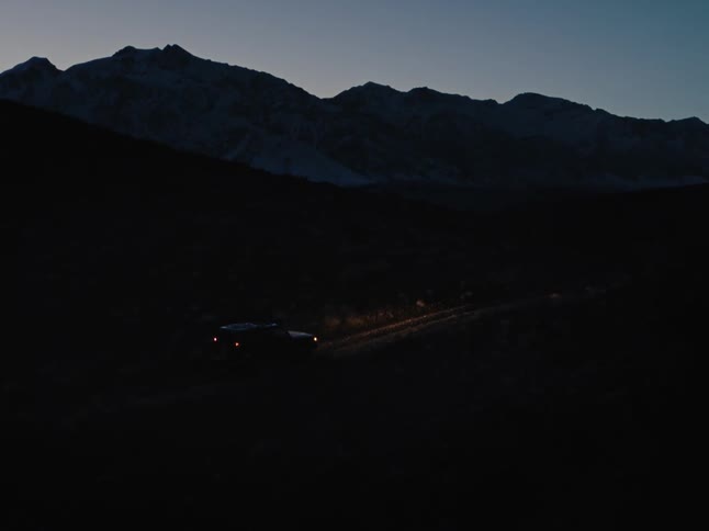 A vehicle is driving off road at sunset