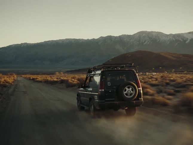 A vehicle drives down a road in a desert