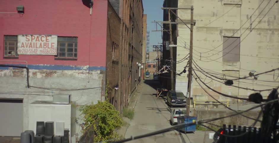 A narrow street with a car parked between two old buildings