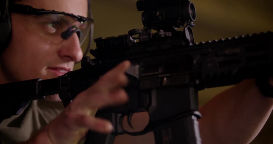 A man fires an automatic weapon at a gun range
