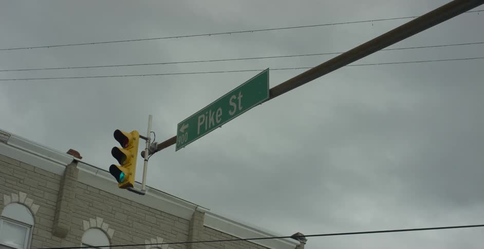 Traffic signal glows green in intersection near building on an overcast day