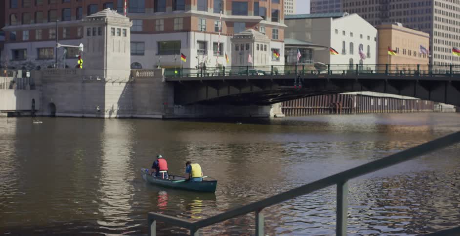 Two people sitting on a boat on a river near the milwaukee drawbridge