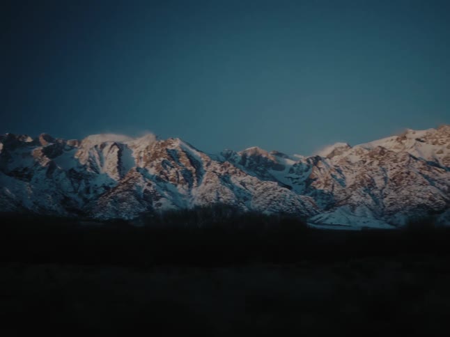 A mountain range covered in snow on a dark morning