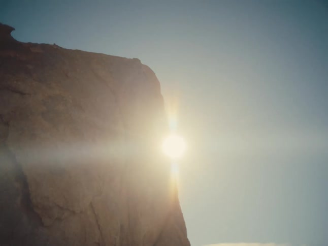 The sun is glaring over the cliff