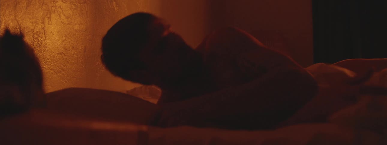 Man leaning against pillows in bed at night removes extra pillow and lies down