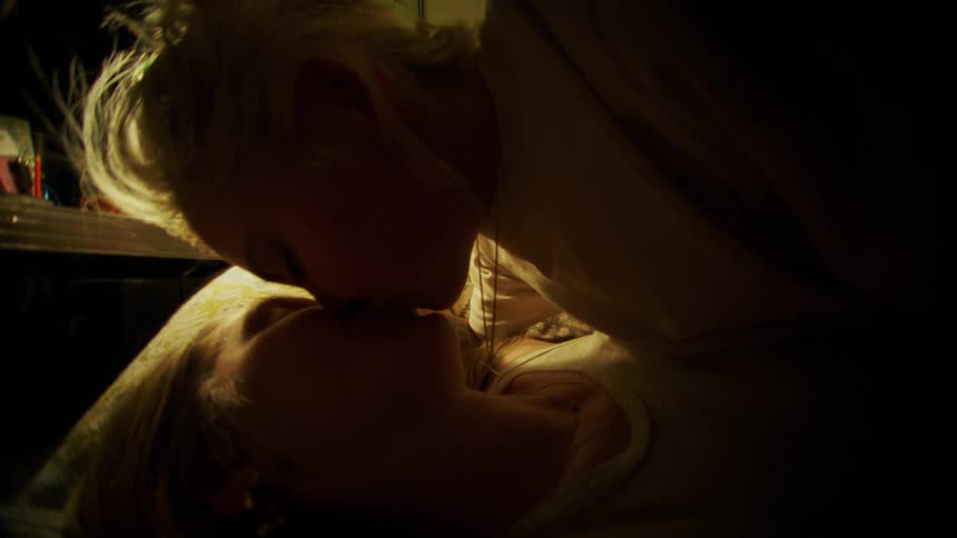 Two young women in a bed embracing and kissing