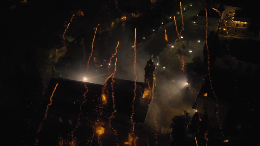 Fireworks shooting above houses at night with smoke all over