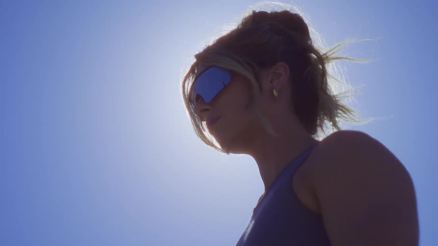 Side portrait of a woman with sunglasses stretching her arms in an openair environment