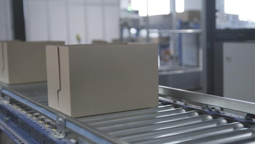 Two cardboard boxes passing on a silver industrial conveyor belt