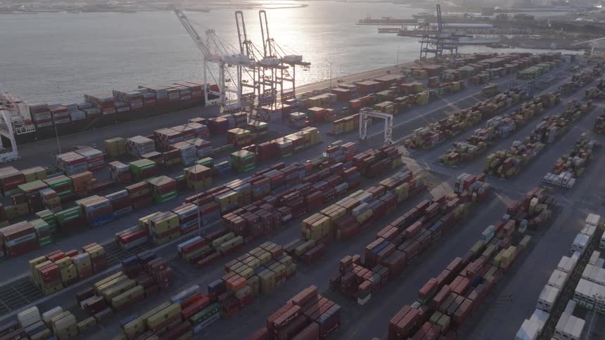 Aerial of shipping containers near a port at sunset