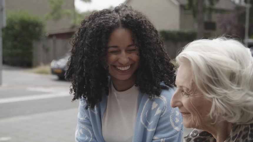 A young woman helps an elderly lady to cross the street