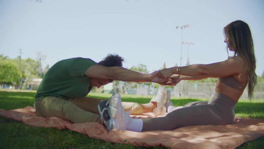 A man and woman stretch together outdoors