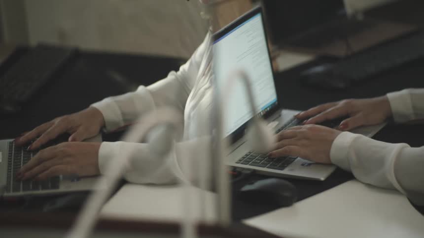 A person working on a laptop reflected on a mirror