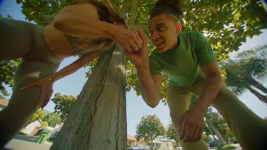 Woman shakes teenage boys hand as they rest under a tree
