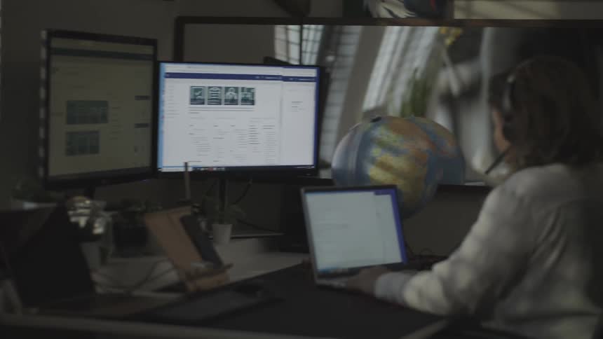 Woman with headset typing on her laptop in an office room