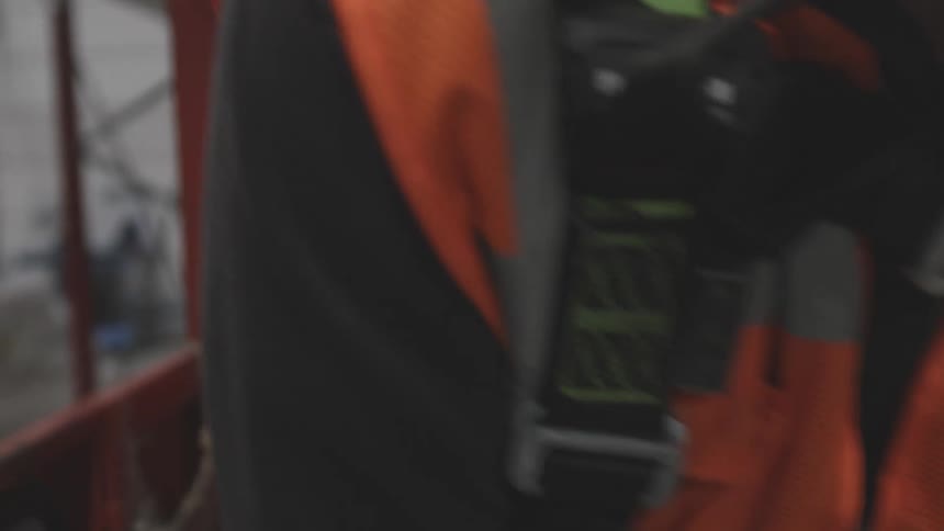 Hands of a man fastening a seat belt on an orange vest he is wearing