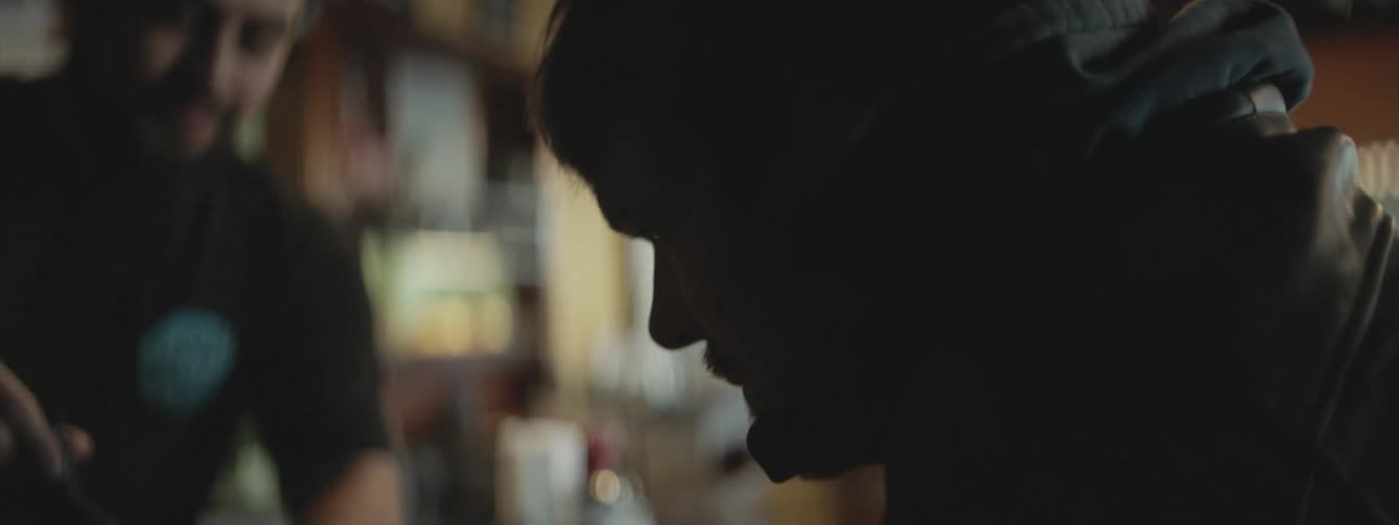 Man in a hoodie inside a bar calling the waiter and having a hot drink