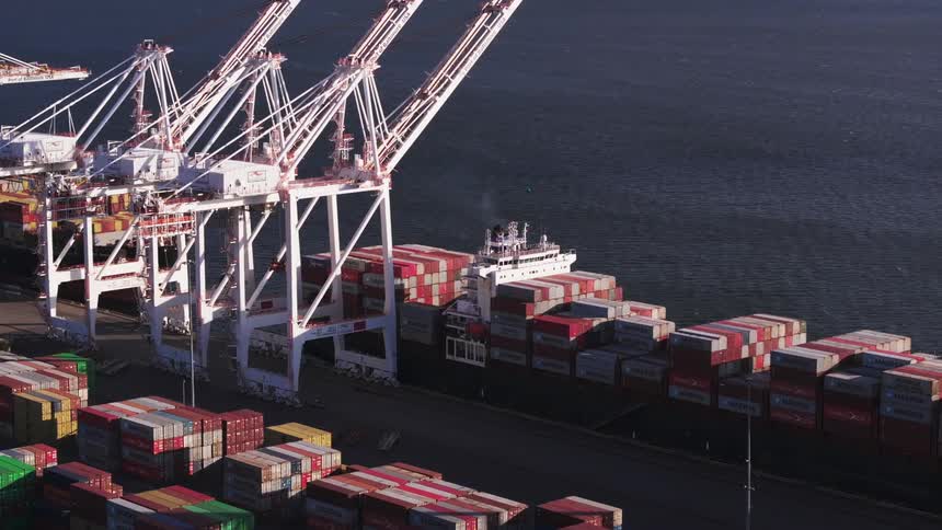 A port with a ship loaded with containers and next to it there are large white cranes