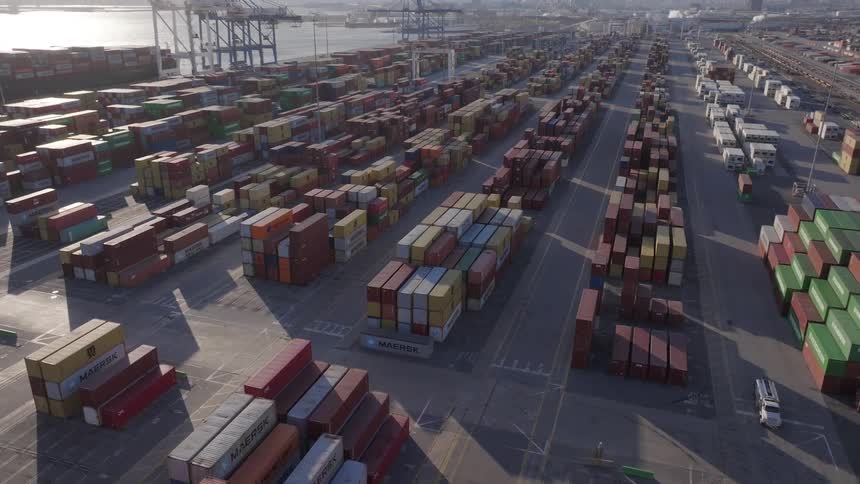Storage containers stacked up by a port near a city