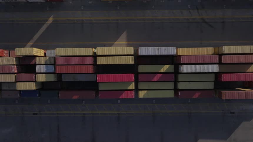 Aerial of large shipping containers stacked neatly in rows in a container depot