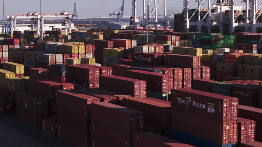 Shipping containers stacked high in a port facility on a coast