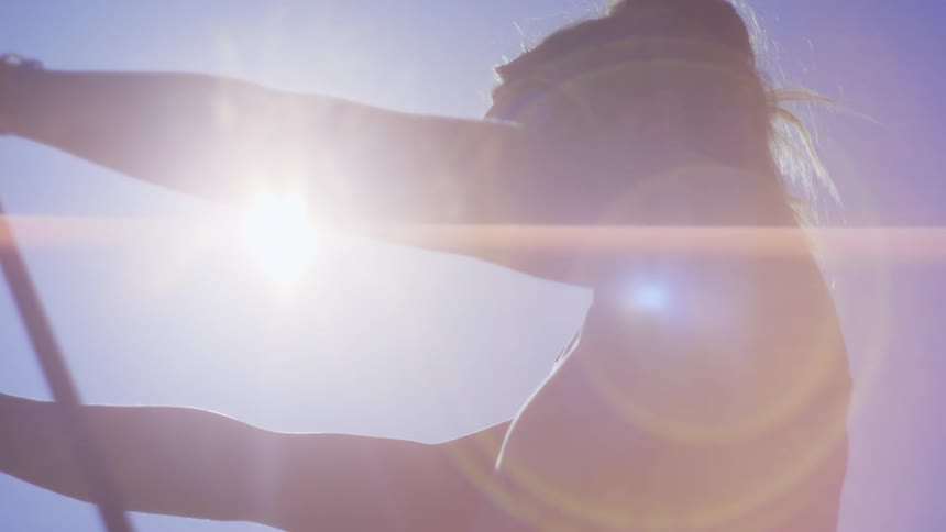 A young fit woman wearing sports clothes stretches under the sun