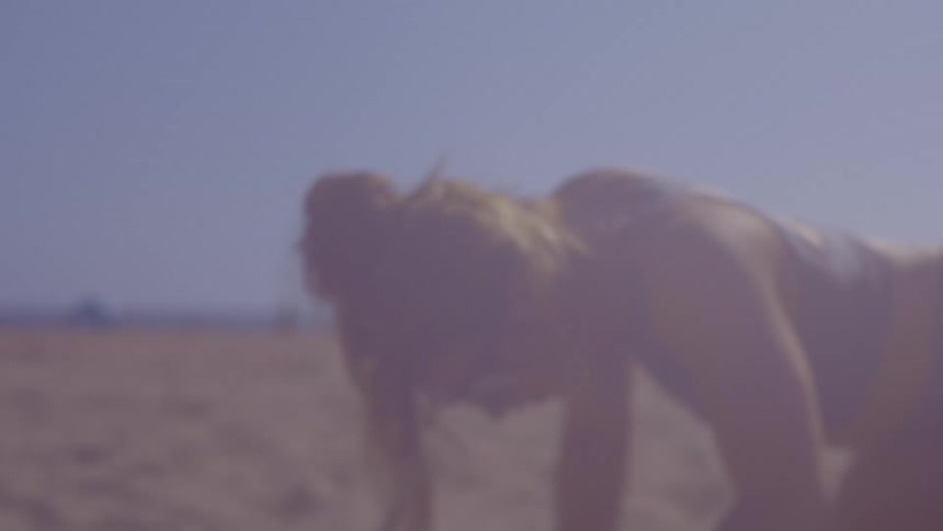 Woman crouching on the beach sand stretching her body on a summer day