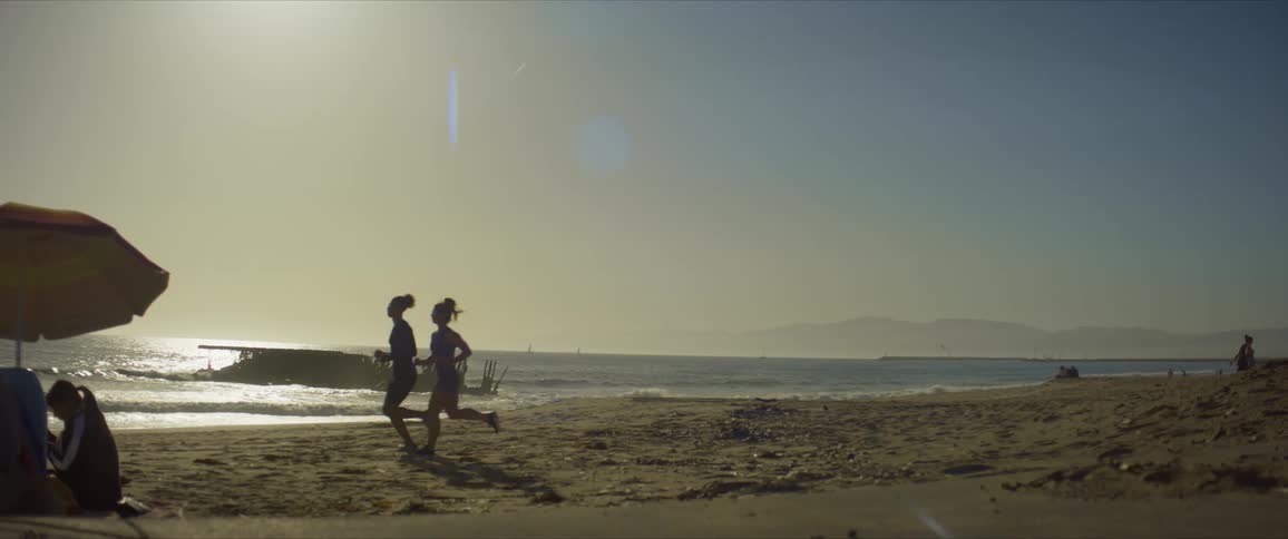 Two women run on the beach