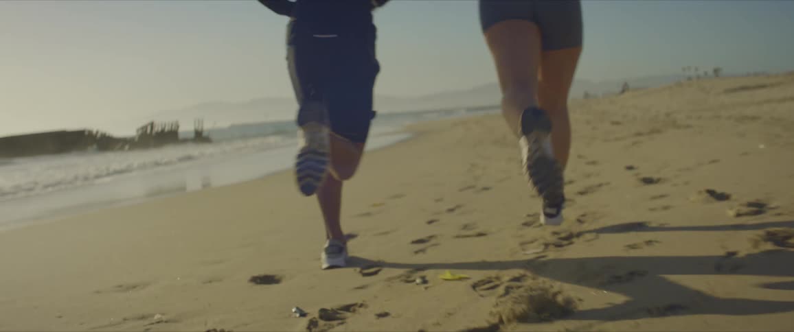 Man and woman running on the beach sand