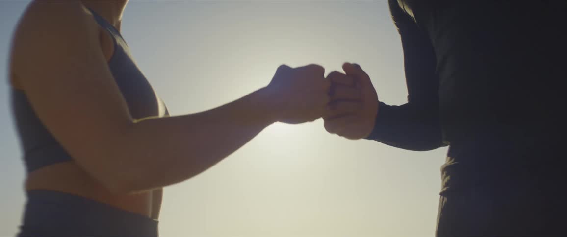Male and female fist bumping after a workout outdoors