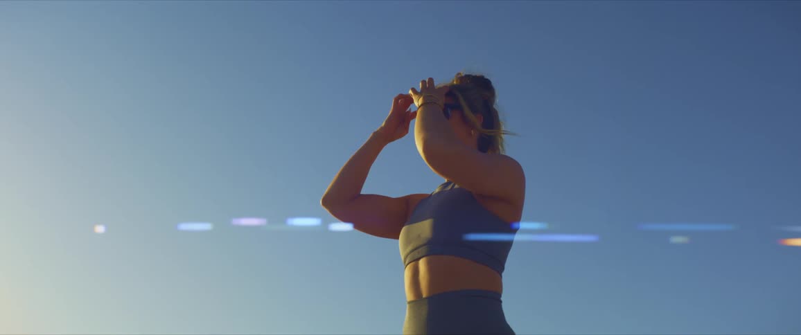 Smiling woman in sportswear and sunglasses in an outdoor setting