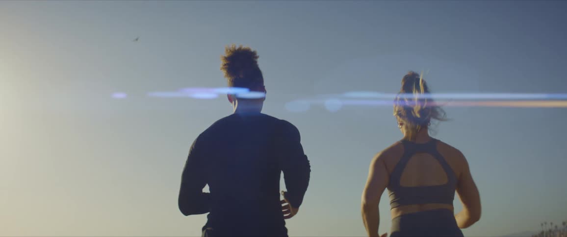 View of a man and a woman running side by side on the beach sand
