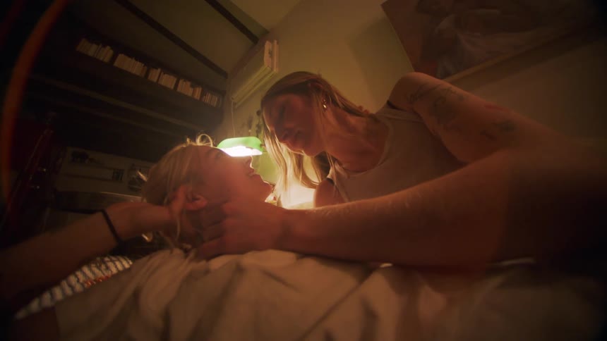Women lying together smile and stroke each others heads