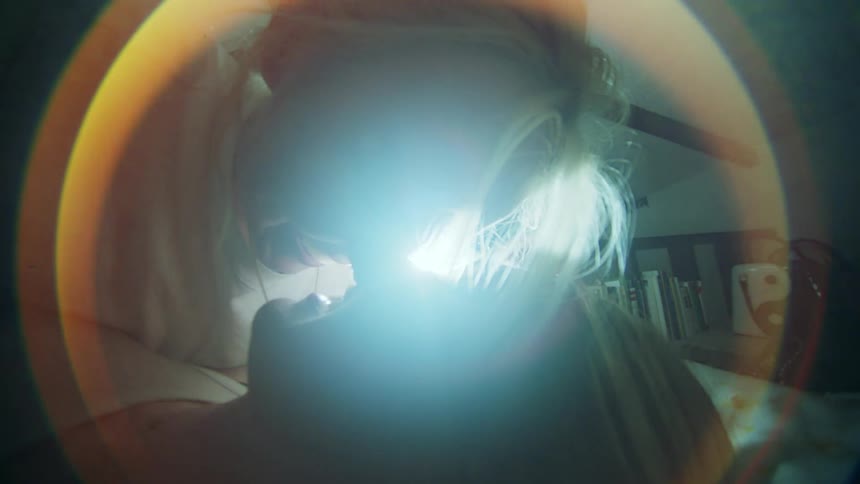 Two women lying down kissing inside the room with sunlight reflected