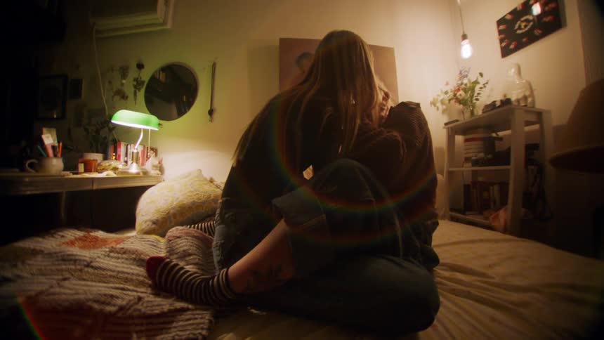 Two women sitting on the bed and kissing
