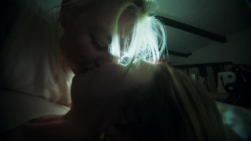 Young couple lying in bed kissing in a dimly lit bedroom