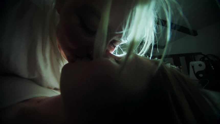 Portrait of two smiling women lying down kissing