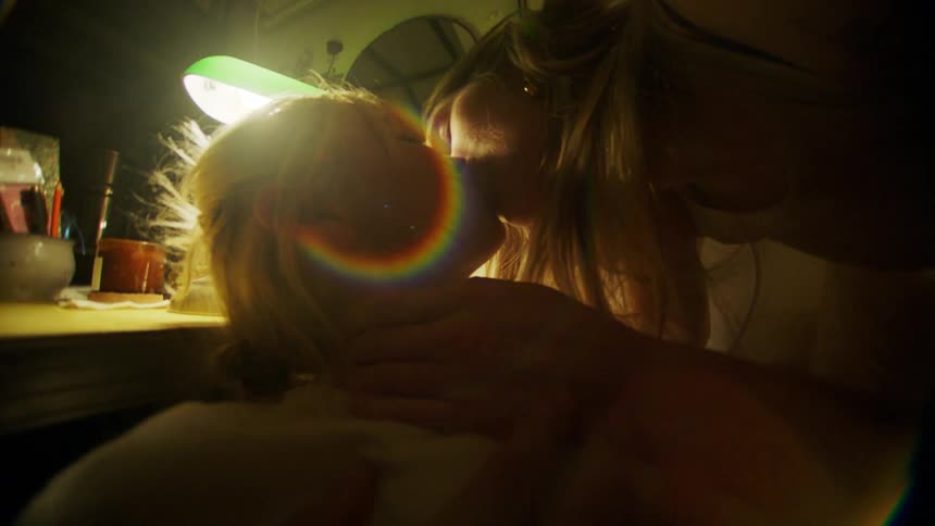 Two women kiss in a bed