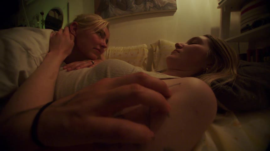 Woman lying on top of another woman making affection in a romantic way
