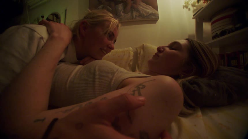 A woman lies on another woman touching and stroking each other as they laugh together