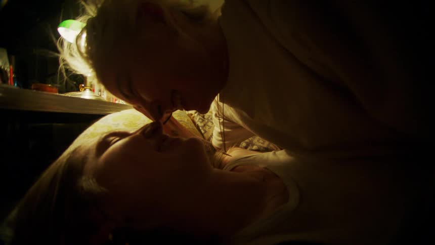Two women smiling and staring into each others eyes on a bed