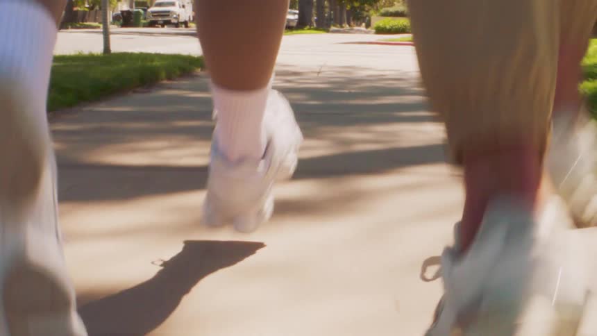Feet of a man and a woman with sneakers running on the sidewalk of a residential neighborhood