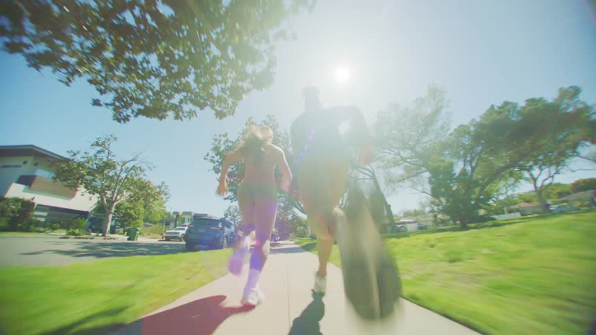 Man and woman side by side running on the sidewalk of a residential neighborhood with trees around