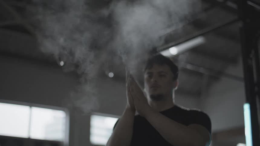 Concentrated man clapping his hands with magnesium inside a shed