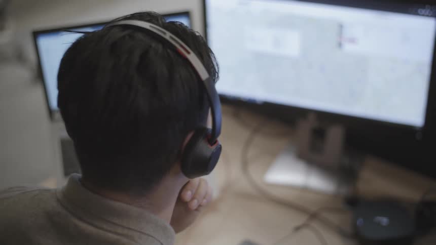 Office worker sitting at table examines multiple computer screens