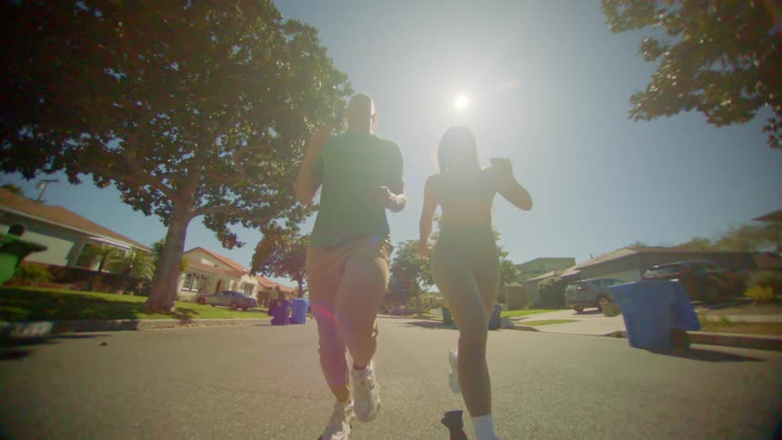Man and woman running side by side on the street of a residential neighborhood during the day