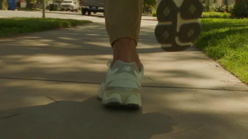 Person wearing white running shoes jogging on a sidewalk
