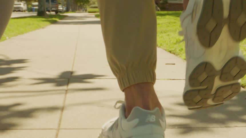 A man and a woman running on a sidewalk in a suburb
