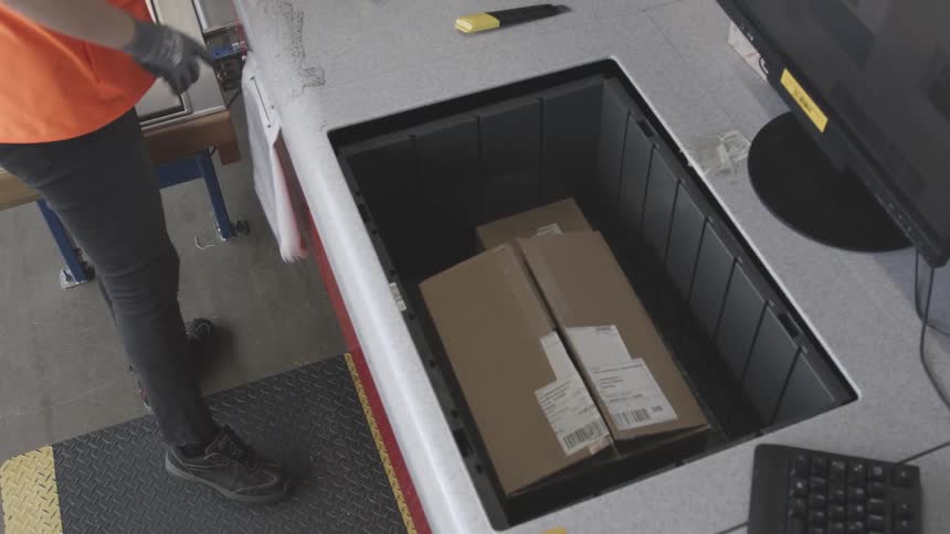 A female employee lifts boxes out of containers at her job
