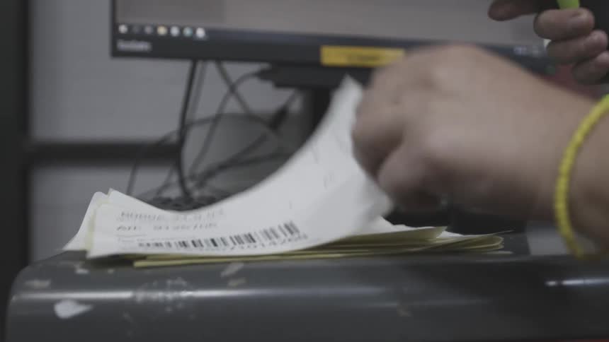 The hand of a person who takes a barcode reader from a piece of paper and reads it
